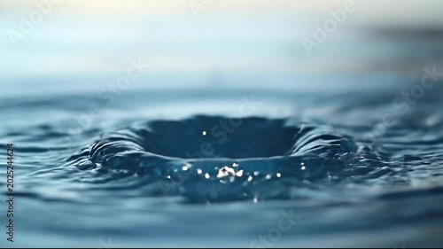 Water droplet creating splash in a serene blue background