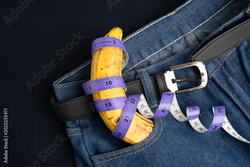 Banana with measuring tape on jean trousers, penis health.