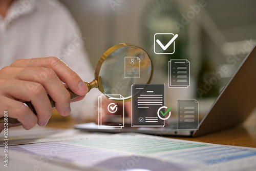 businessman holding magnifying glass looking at virtual data chart dashboard in concept of investment data analysis and DMS document audit financial Tax Fraud audit Using Magnifying Glass