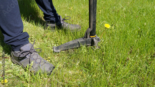 Photos Gardener removing dandelion with stand up weed puller tool