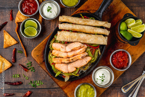 Overhead view of grilled salmon fajita served in skillet with tortillas