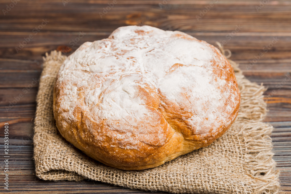 Naklejka premium freshly baked bread with napkin on rustic table top view. Healthy white bread loaf isolated