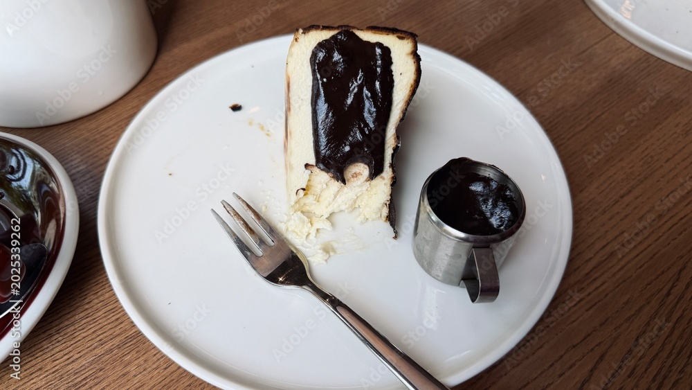 Naklejka premium Top view of San Sebastian burnt Basque cheesecake slice with chocolate sauce on a plate