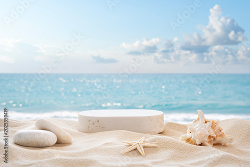 White round stone podium on sand beach with blurred tropical summer sea and sky as background