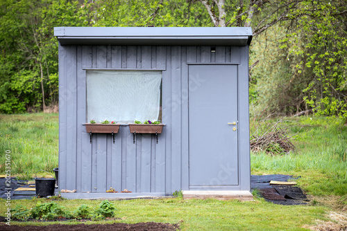 Modern Gray Garden Shed With Window and Door in Green Backyard