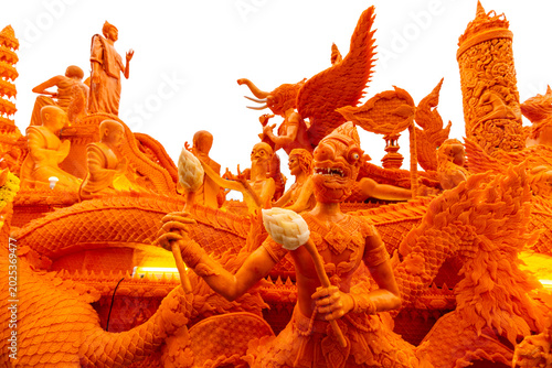 Canvas-taulu Intricate orange wax sculpture float featuring mythical Thai figures and Buddhist elements for a traditional festival