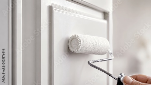 Hands painting kitchen cabinet door with roller revealing modern finished cabinet surface