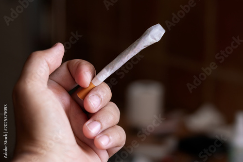Photos Hand holding a marijuana rolling cigarette