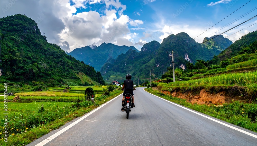 Obraz premium Motorcyclist riding through scenic mountain landscape under cloudy sky