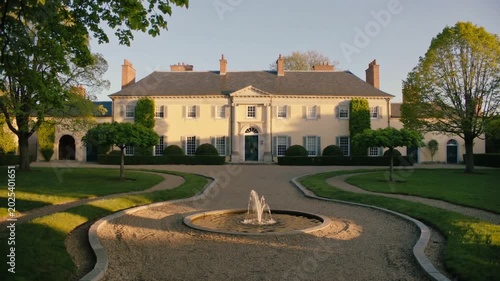 Moving camera revealing two-story mansion at courtyard with gravel drive, showing fountain jets