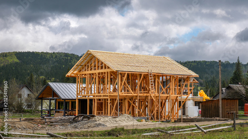 Foto Wooden house frame construction in a rural mountainous landscape under cloudy sk