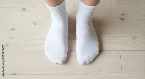 Person wearing white socks standing on wooden floor indoors