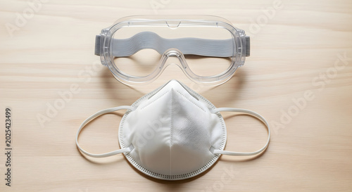 Protective gear including safety goggles and face mask on wooden table