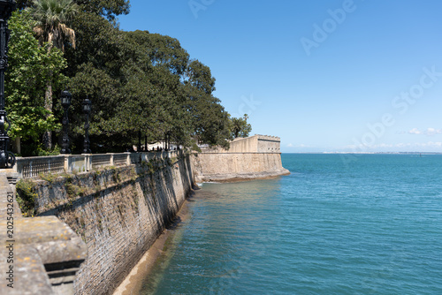 Tableau sur toile Historic sea wall and boardwalk along the Atlantic Ocean in Cádiz, Spain, offeri