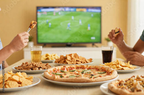 A Group of People Sitting Around a Table Eating Pizza and Chips