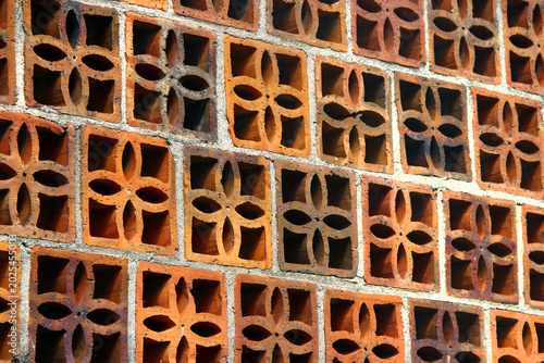 Patterned terracotta ventilation brick wall with geometric floral openings and textured masonry details