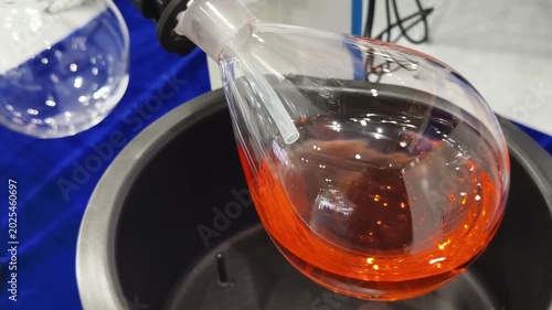 Chemical reaction demonstration showing colorful liquid in glass container near equipment in lab setting