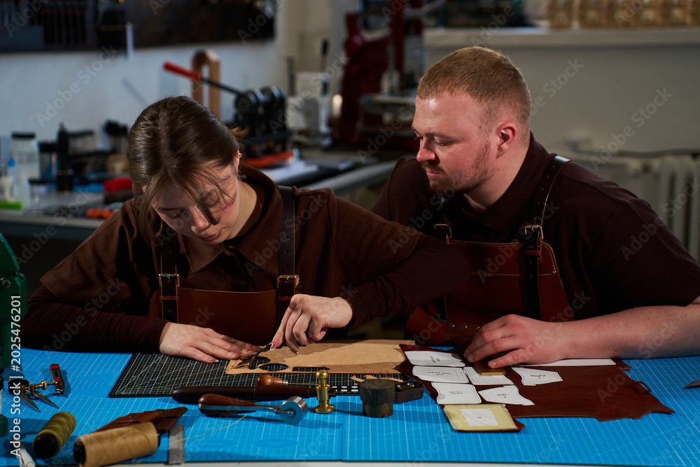 Fototapeta premium Collaborative workshop with leatherworkers cutting patterns on leather.