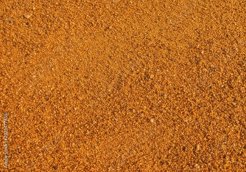 A detailed close-up of warm, reddish-gold grains of natural beach aggregate, forming a textured background for travel or construction concepts ,reddish ,closeup ,abstract