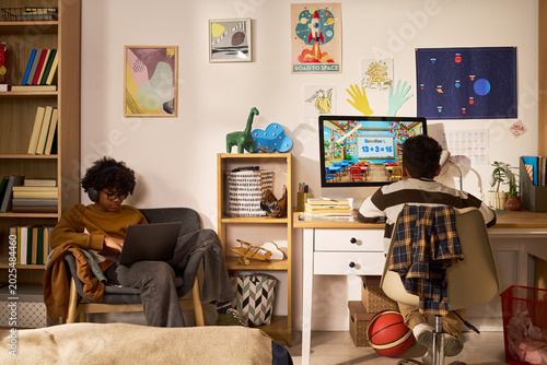 Fotografie African American teenager studying on laptop while younger boy attending online