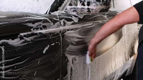 Manual washing of car. Man washes car with foam sponge