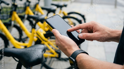 Ecological urban transit bicycle smartphone app cyclist hand touchscreen bike share station rain. Eco friendly mobility. sustainable commuting innovation, future system efficiency
