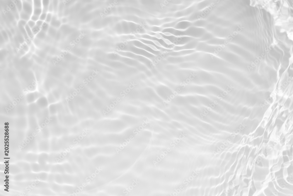 Fototapeta premium White water with ripples on the surface. Defocus blurred transparent white colored clear calm water surface texture with splashes and bubbles. Water waves with shining pattern texture background.