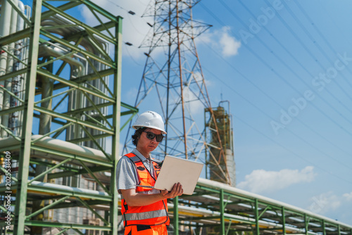 Oil and gas refinery in petroleum industry with inspection engineer, industrial engineer site inspection with laptop near power plant, focused and alert
