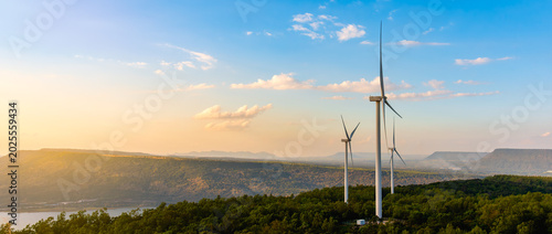 Beautiful sunset landscape of a wind farm on green hills with turbines. Clean renewable energy production and sustainable power generation at golden hour.