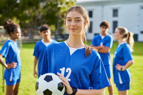 Portrait of focused soccer female player holding football ball