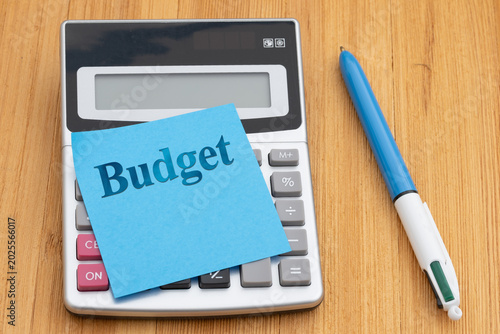 Obraz na plátne Budget message with calculator and sticky note and pen on wood desk