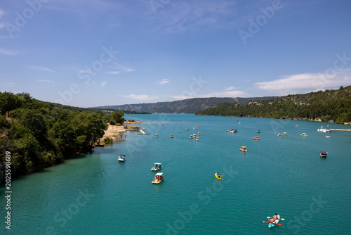 Tourists sail on the Lake of Sainte-Croix in pedal boats, kayaks and paddle boats. An ideal place for an active holiday in Provence-Alpes-Côte d'Azur, France.