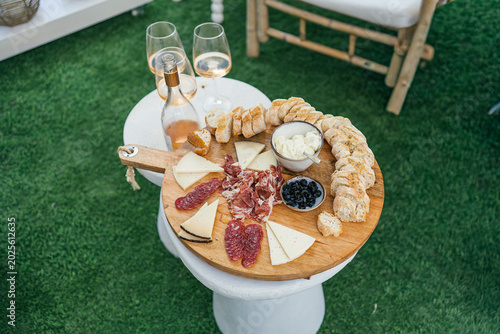Canvastavla Charcuterie board with cured meats, cheese, olives and rose wine on a garden ped