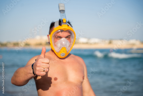 Vászonkép Caucasian man wearing snorkeling mask shows thumbs up in Red Sea water near Sharm El Sheikh Egypt during summer vacation