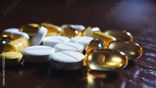 Close-up of assorted pills and supplements on a dark wooden surface, representing healthcare and medication.