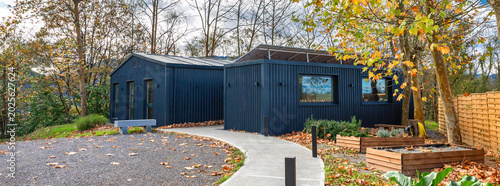 Banner of sustainable coworking office building using shipping containers, featuring solar panels, blending contemporary sustainable architecture with the surrounding autumn nature of forest