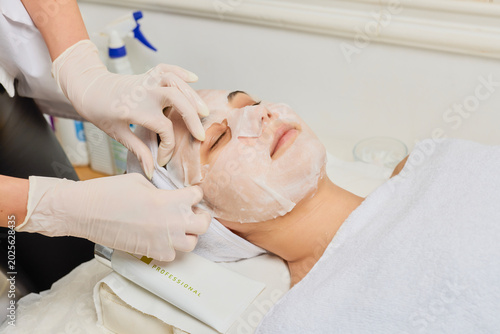 Billede på lærred picture of a young woman at a beauty salon where she is being given a paper mask