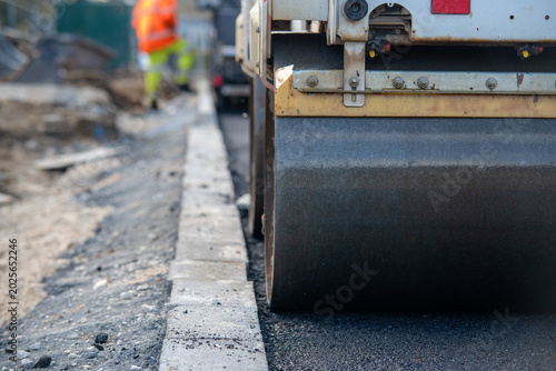 Photos Heavy roller compactor works on new road construction in a busy urban area durin
