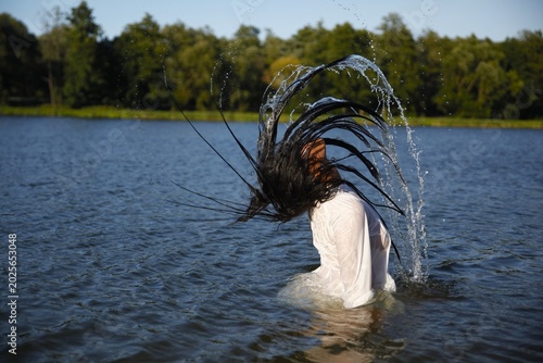 Woman Flipping Wet Hair Back in Water
Female Splashing Water with Hair Flip
Beautiful Woman Tossing Hair in Lake
Dynamic Water Splash Portrait of Woman