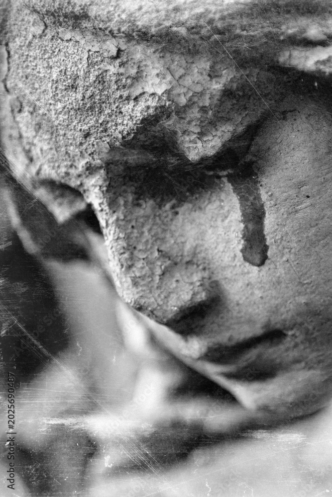 Fototapeta premium Crying stone angel with dark tear stain in emotional monochrome atmosphere