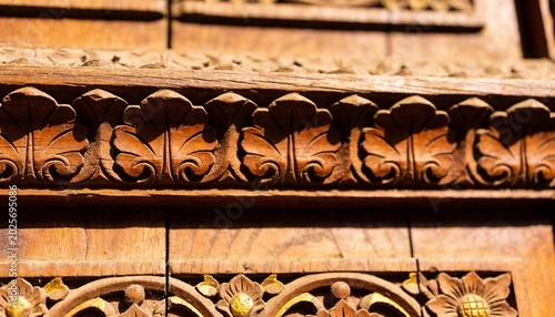 Showing ornate carved wooden frieze revealing deep shadows in close-up, with gilded floral rosettes