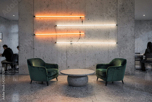 Modern Industrial Lounge Interior with Green Velvet Armchairs and Neon Lights on Concrete Wall