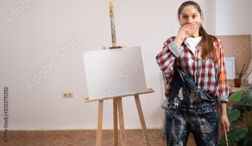 Foto Shocked female artist covering mouth with hand in unpleasant surprise or horror concept
