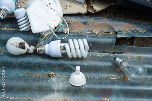 Fotografi Various types of broken light bulbs and waste materials are seen on a metal surface in an outdoor area