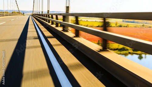 Drawing eye along asphalt bridge lane with white center stripe, guardrail, suspension cables ahead