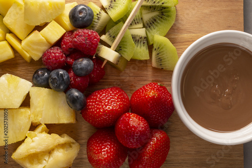 Canvastavla Fresh fruit platter with chocolate dip and skewers on wooden board, strawberries