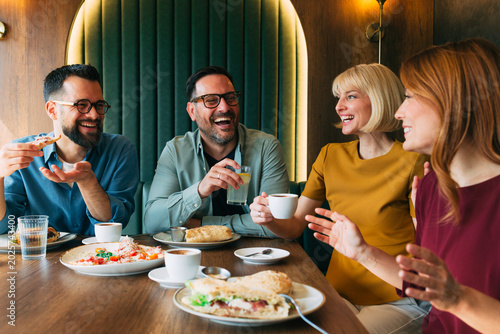 Diverse group of friends laughing and eating together during a social brunch