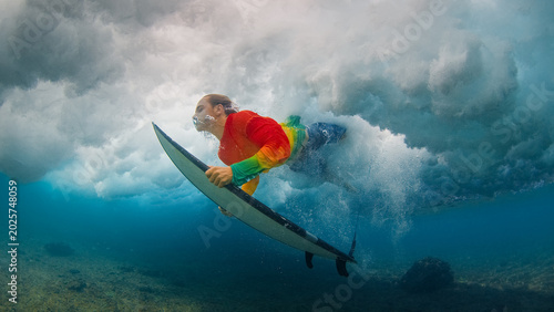 Canvas Print Teen boy surfer passes the wave doing duck dive trick in the ocean in the Maldives with surfing board