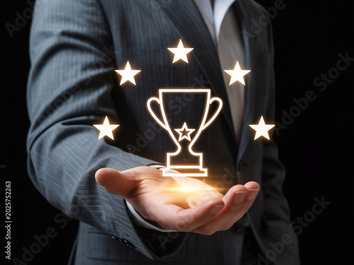 Businessman holding trophy icon with stars for achievement and success concept, glowing award symbol