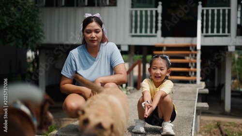 Foto Mother and daughter enjoying playtime with pet dogs outdoors at home